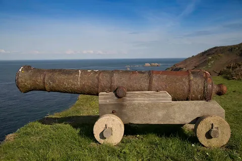 An old cannon on a grassy clifftop pointing out to sea, Sark, Channel Islands