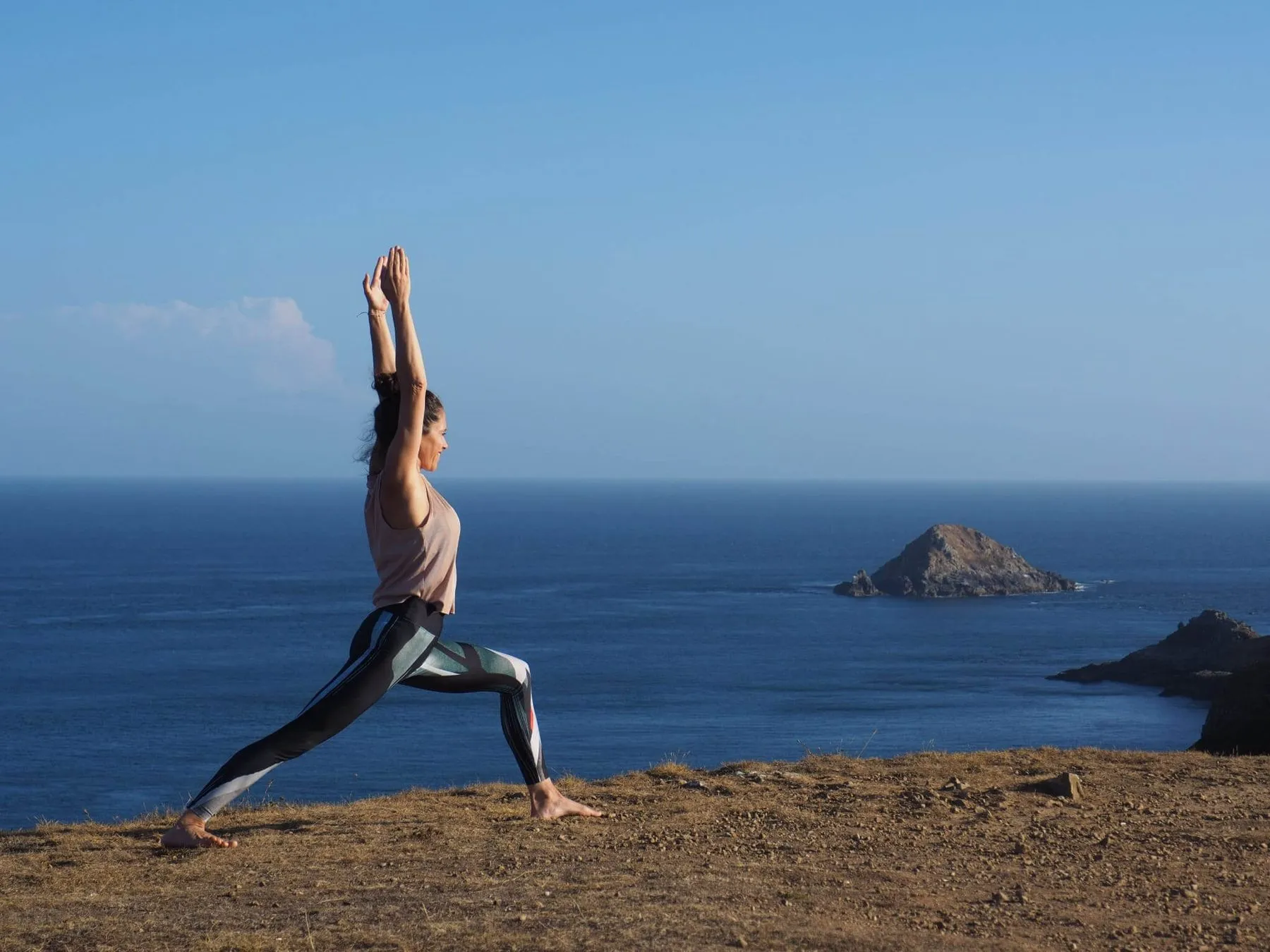 Warrior pose on the clifftop above the sea on Sark, Channel Islands