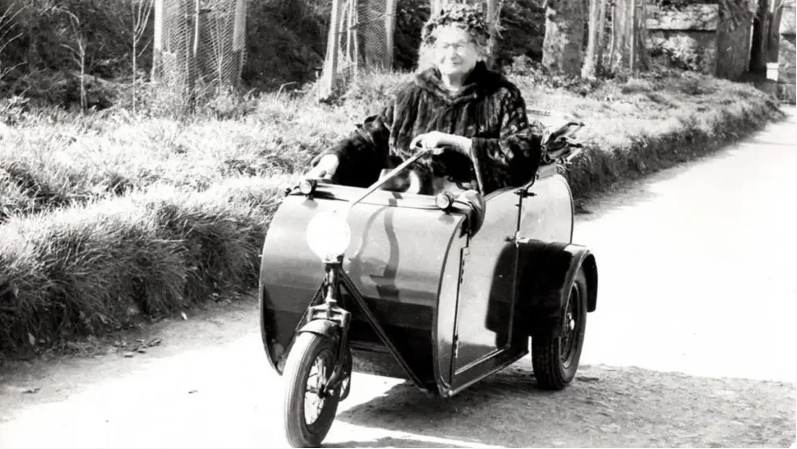 Dame Sibyl Collings riding in a motorised sidecar on a Sark lane in later life