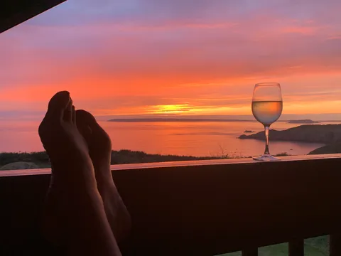 Feet up with a glass of wine, watching the sunset over the sea on Sark