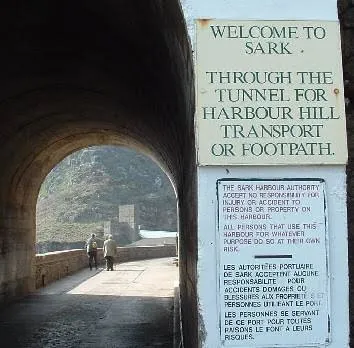 The harbour tunnel with its Welcome to Sark board, two people walking through, Sark, Channel Islands