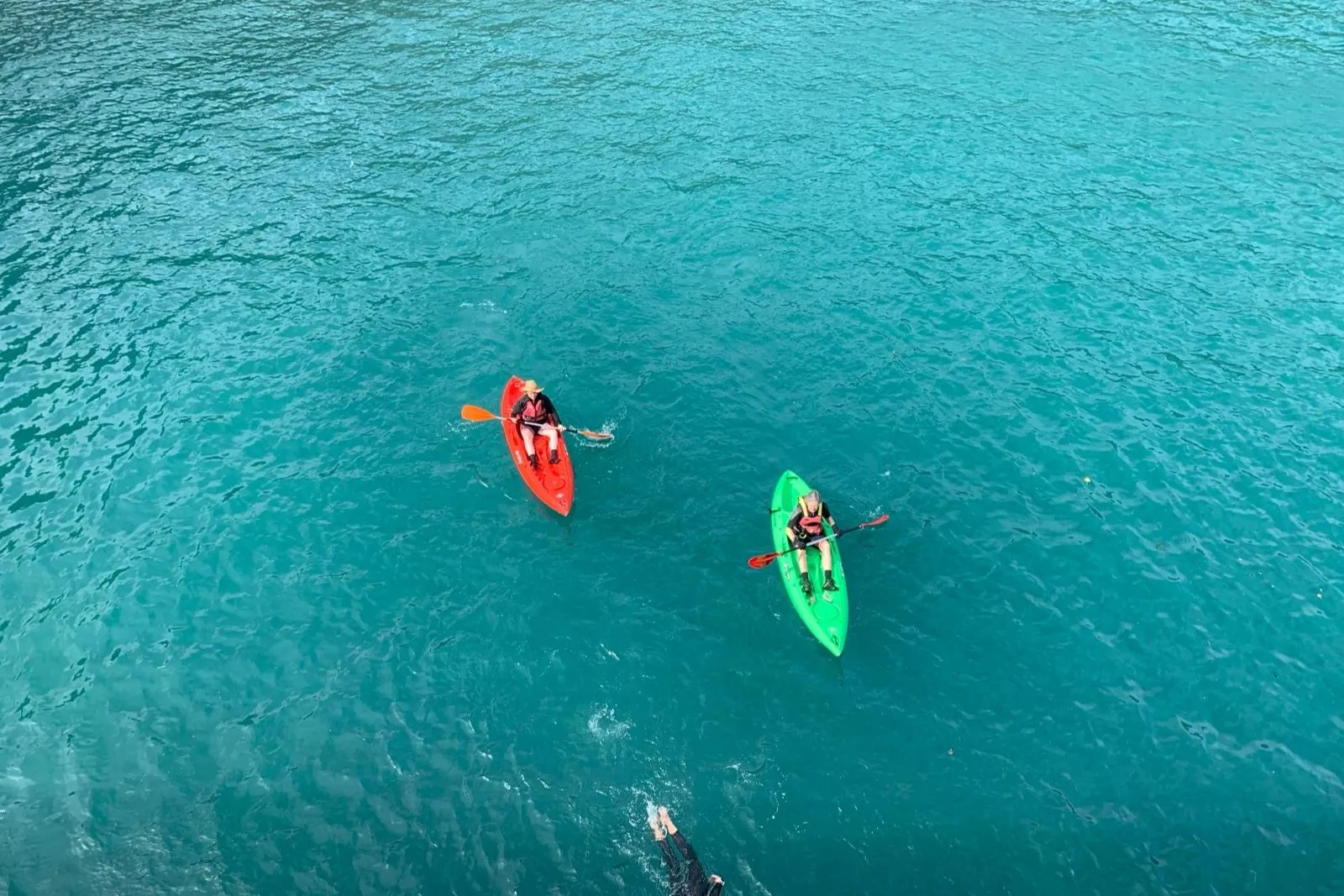 Kayaks and a swimmer in turquoise water off Sark