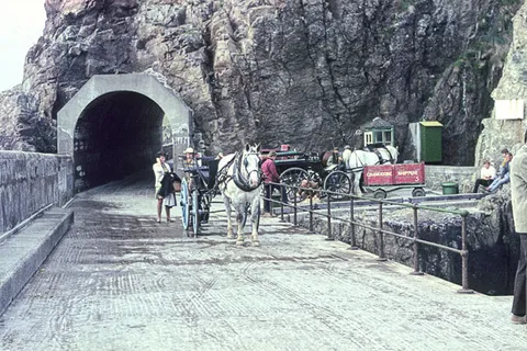 Horse-drawn carriages waiting at the tunnel entrance to Maseline Harbour, Sark, Channel Islands