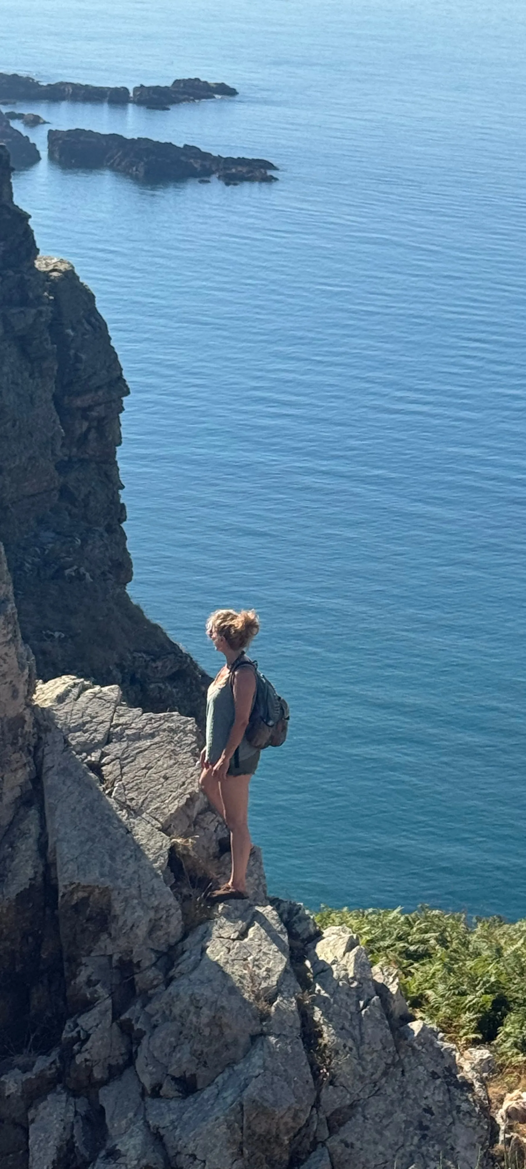 Nadia standing on a clifftop above the sea on Sark, Channel Islands