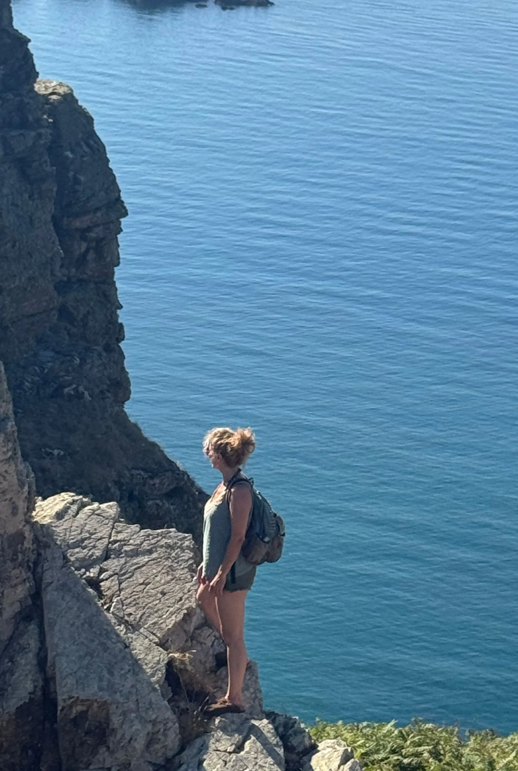 Nadia standing alone at a clifftop lookout on Sark