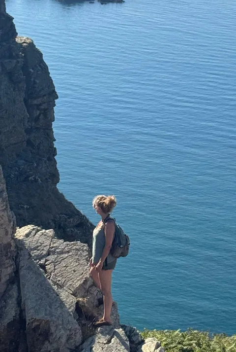 Nadia standing alone at a clifftop lookout on Sark
