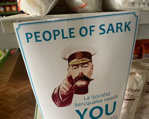 A printed notice in a Sark shop headed People of Sark, showing a Kitchener style pointing figure and the words La Société Sercquaise needs YOU, appealing for volunteers, Sark, Channel Islands