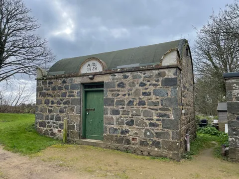 The two-cell Sark prison, built 1856, with its barrel roof, green door and AD 1856 date stone, Channel Islands