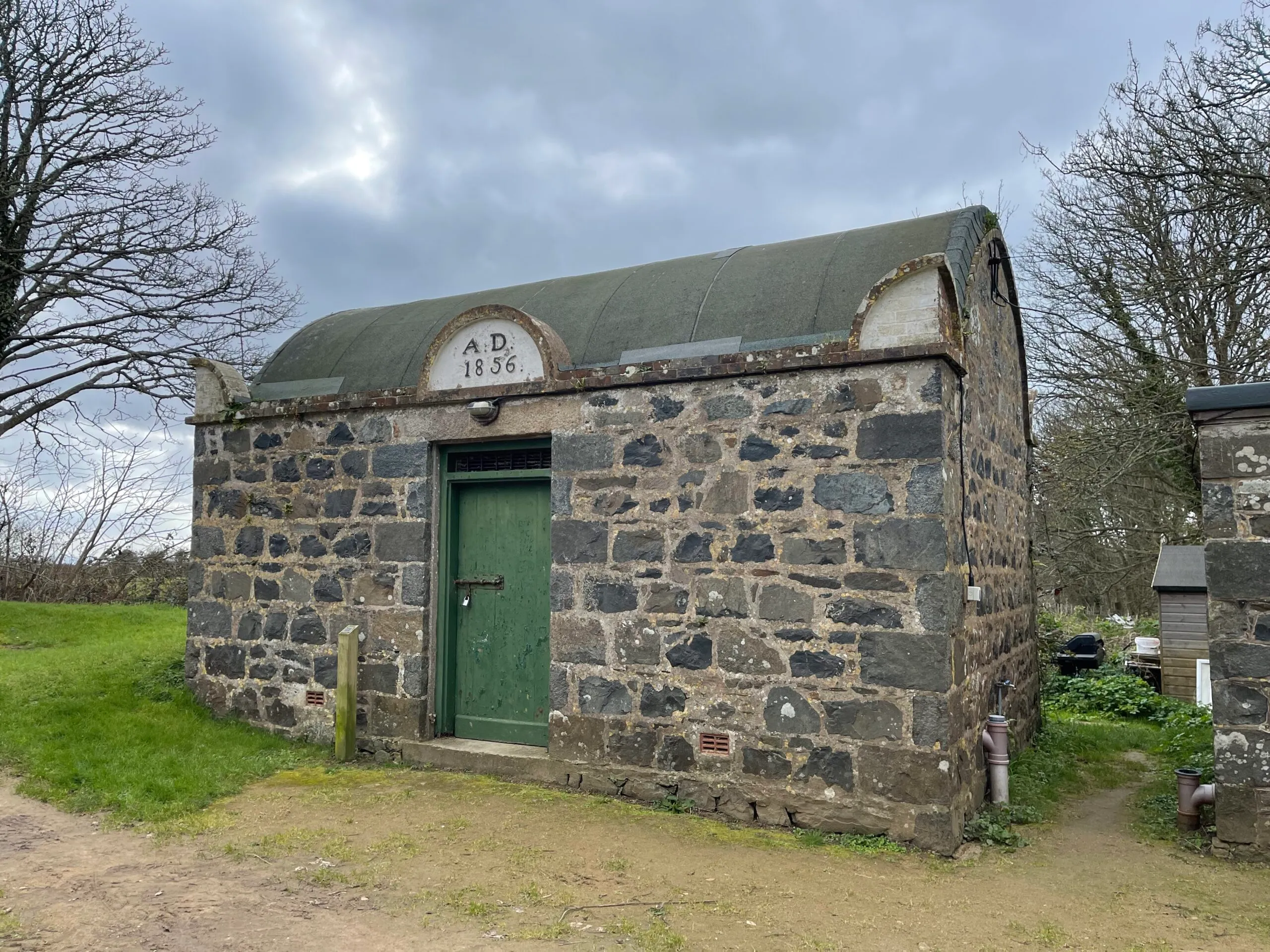 The two-cell Sark prison, built 1856, with its barrel roof, green door and AD 1856 date stone, Channel Islands