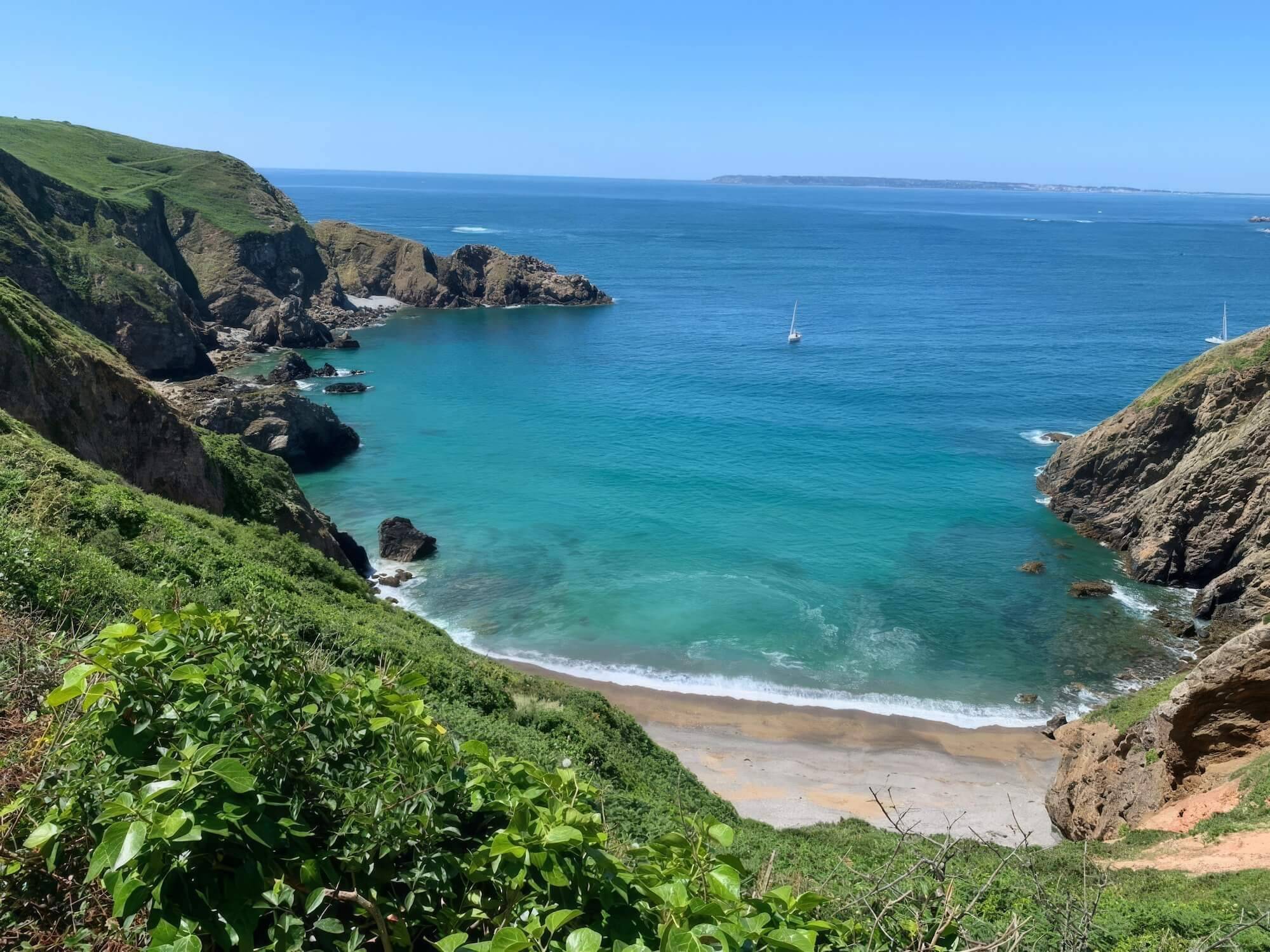 Yachts at anchor in a turquoise bay below the cliffs of Sark, Channel Islands