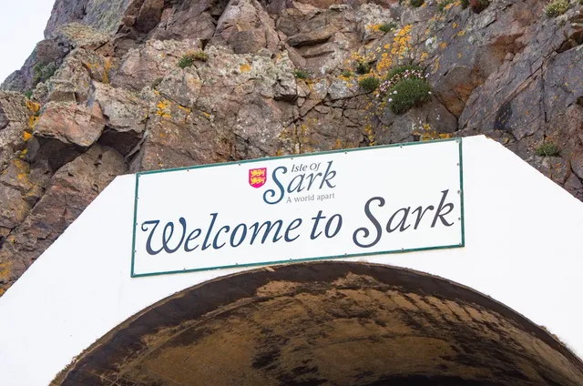 The Welcome to Sark sign above the harbour tunnel, rock face behind, Sark, Channel Islands