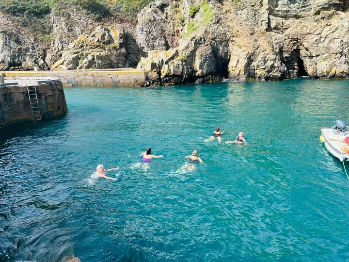 Guests swimming in a sheltered cove on Sark
