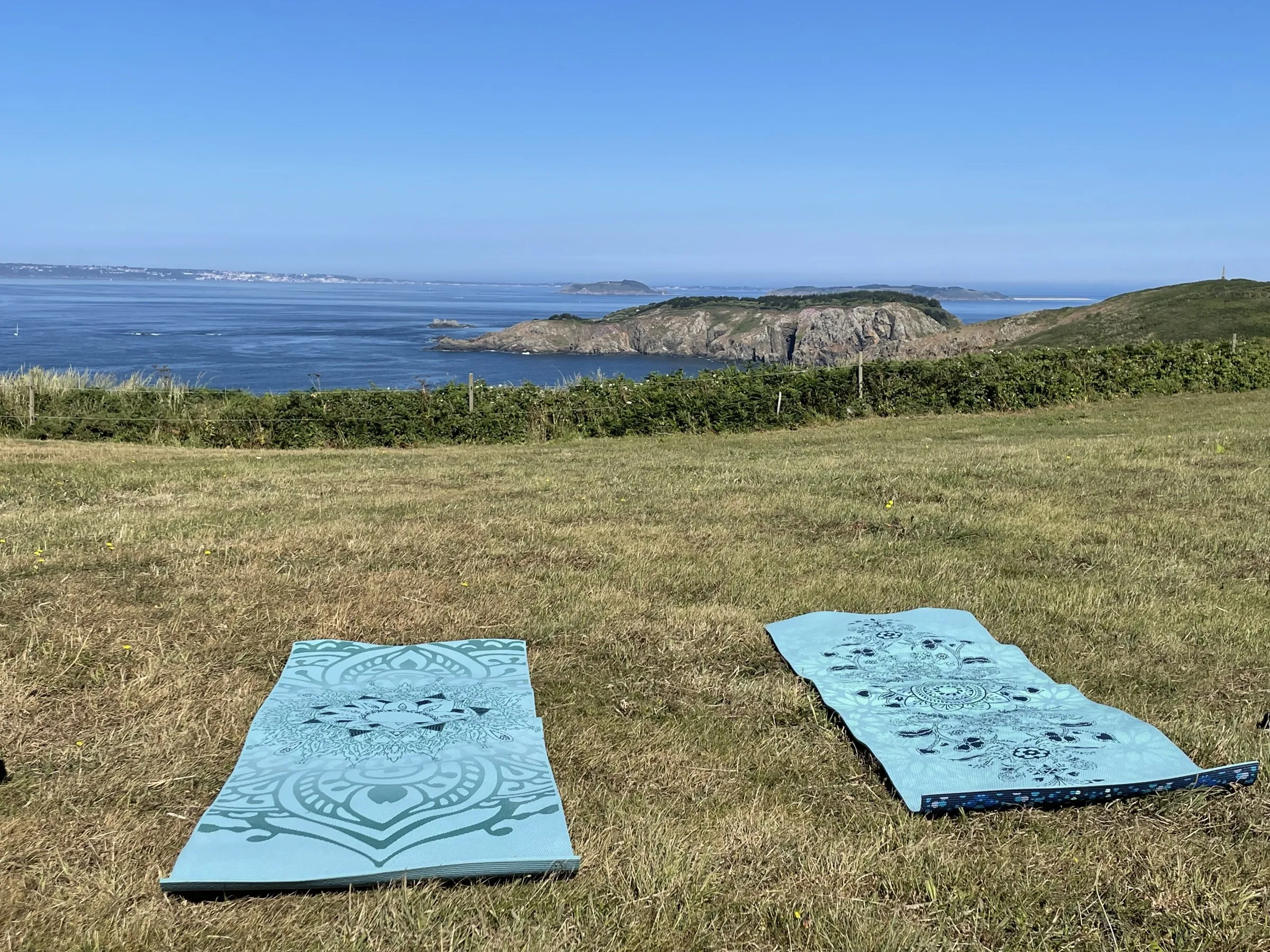 Two yoga mats laid out on a Sark clifftop looking over the sea