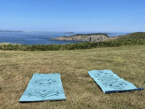 Two yoga mats laid out on a Sark clifftop looking over the sea